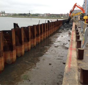 The mixing process taking place between the new quay sheet piles and the existing quay edge. The excavator in the fore front is checking ahead of the main mixing tool to establish depth to the firm sand layer and also to remove any obstructions.